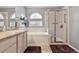 Bright bathroom featuring a soaking tub with a shower, a single sink vanity, and tiled floors at 4819 Jericho Ct, Denver, CO 80249