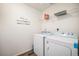 Well-lit laundry room featuring a modern washer and dryer, shelving, and attractive wall decor at 47356 Lilac Ave, Bennett, CO 80102