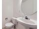 Bathroom featuring a pedestal sink, a round mirror, and a toilet with modern white fixtures for a clean design at 4555 S Auckland Ct, Aurora, CO 80015