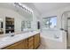 Bathroom with double sinks, a large mirror, a tub, and a shower, providing a relaxing and functional space at 4555 S Auckland Ct, Aurora, CO 80015