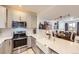 Modern kitchen with stainless steel appliances, white countertops, and subway tile backsplash, with an open view into the dining room at 4555 S Auckland Ct, Aurora, CO 80015