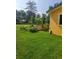 Exterior shot of the backyard featuring healthy green lawn, landscaping, and charming yellow house at 26259 Kingsbury Rd, Kittredge, CO 80457