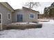 Backyard showing exterior with blue french doors and snow-covered ground, complete with windowed basement access at 26259 Kingsbury Rd, Kittredge, CO 80457