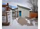 Gray house with teal door, snow on ground, wooden fence, and real estate sign at 26259 Kingsbury Rd, Kittredge, CO 80457