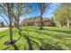 Beautiful brick home with a lush green lawn, mature trees, and a serene setting on a sunny day at 6116 W Frost Dr, Littleton, CO 80128