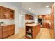 Gourmet kitchen boasts wood cabinets, an island with cooktop, granite counters, and stainless steel appliances at 6116 W Frost Dr, Littleton, CO 80128
