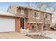 Charming front exterior with a brick facade, white garage door, and decorative door wreath at 9240 W Wagon Trail Dr, Littleton, CO 80123