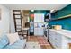 Stylish living area with a gray cabineted kitchen, mini fridge, and a wooden ladder leading to a loft space at 949 Raleigh St # 2, Denver, CO 80204