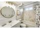 Updated bathroom with a modern vanity, gold round mirror, and gray-and-white marbled tile shower at 1422 Ivy St, Denver, CO 80220