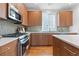 Kitchen area featuring modern appliances, wood cabinets, tile backsplash, and hardwood floors at 8711 E Hampden Ave # 21, Denver, CO 80231