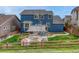 Backyard view of a blue house, showing a patio with shade, grass, and a wooden fence at 3367 Dove Valley Pl, Castle Rock, CO 80108
