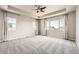 Light-filled main bedroom boasts a tray ceiling, carpet, and multiple windows with scenic views and natural light at 6612 S Muscadine Ct, Aurora, CO 80016