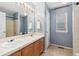 Bright bathroom featuring a double sink vanity, a large mirror, and a separate shower at 19823 E 58Th Ave, Aurora, CO 80019