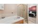 Bright bathroom featuring a bathtub, a glass-enclosed shower, and a view to the main bedroom at 19823 E 58Th Ave, Aurora, CO 80019
