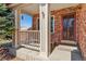 Inviting covered front porch with seating area and security camera at 19823 E 58Th Ave, Aurora, CO 80019