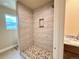 Modern tiled shower with pebble stone floor, built-in niche, and adjustable shower head, offering a luxurious experience at 826 Meadow Ln, Palmer Lake, CO 80133