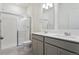 Well-lit bathroom with double sinks, gray cabinets, and a glass enclosed shower at 6500 13Th St, Frederick, CO 80530