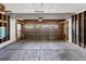 A spacious garage with a concrete floor, open framework, and paneled garage door with visible hardware at 8414 Bed Straw St, Parker, CO 80134