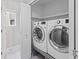 Functional laundry room with modern front-load washer and dryer, and storage shelves at 8414 Bed Straw St, Parker, CO 80134