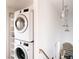 Bright laundry area with stacked washer and dryer and convenient shelving at 3746 Jason St, Denver, CO 80211