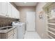 Bright laundry room features front load machines, overhead white cabinets, granite counter, and neutral patterned tile flooring at 3228 Country Club Pkwy, Castle Rock, CO 80108