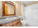 Bathroom features tile countertop, white cabinets, toilet and shower over tub at 10047 Sylvestor Rd, Highlands Ranch, CO 80129