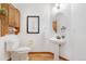 Well-lit powder room featuring a pedestal sink, oak cabinets, and modern fixtures at 10047 Sylvestor Rd, Highlands Ranch, CO 80129