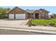 Charming brick home featuring a manicured front yard and a two-car garage with a white door at 1526 Peach Ct, Brighton, CO 80601