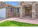 Close up on brick front porch with detailed masonry, manicured lawn, and a stained wooden door at 1526 Peach Ct, Brighton, CO 80601