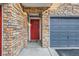 Charming entrance with a red front door, brick accents, and an attached garage, creating a welcoming curb appeal at 2769 W Riverwalk Cir # E, Littleton, CO 80123