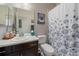 Functional bathroom with a single vanity, toilet, and shower with a floral-patterned curtain at 5437 S Granby Ct, Aurora, CO 80015