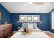 Sun-filled bedroom with a tray on the bed, blue accent wall, three windows, and a wooden dresser at 4590 Grove St, Denver, CO 80211