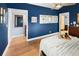 Spacious bedroom with blue walls, wood floors, three windows, and doorways to other rooms at 4590 Grove St, Denver, CO 80211