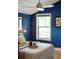 Cozy bedroom with blue accent wall, light fixture, window view and light-colored bedding at 4590 Grove St, Denver, CO 80211