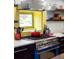 Kitchen with modern appliances, yellow backsplash, stainless steel range hood, and open shelving at 4590 Grove St, Denver, CO 80211