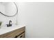 Stylish powder room featuring a round mirror and vanity with modern black hardware at 6722 S Independence St, Littleton, CO 80128