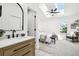Bright bathroom featuring a wood vanity, an arched mirror, and a sneak peak to the light-filled bedroom at 6722 S Independence St, Littleton, CO 80128