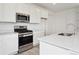 Close-up of kitchen featuring a stainless steel range, microwave, quartz countertops, and white cabinetry at 24780 E 39Th Ave, Aurora, CO 80019