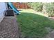 Grassy backyard featuring a slide, lush green lawn, and a well-maintained wooden fence for added privacy at 7988 S Johnson Ct, Littleton, CO 80128