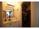 Bright bathroom featuring a vanity with white cabinets, a large mirror, and an organized closet, creating a tidy and functional space at 7988 S Johnson Ct, Littleton, CO 80128