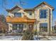 Two-story home with stone and wood accents, a balcony, and a landscaped front yard in winter at 1237 S Saint Paul St, Denver, CO 80210