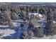 Aerial view of a snow-covered home surrounded by lush pine trees and mountain views at 2880 Lake Meadow Dr, Monument, CO 80132