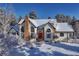 Stunning home with stone chimney, snow-covered roof, and bright red door in a picturesque winter setting at 2880 Lake Meadow Dr, Monument, CO 80132