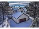 Charming two-story house with a detached garage, covered in snow, surrounded by tall pine trees at 2880 Lake Meadow Dr, Monument, CO 80132