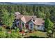 Charming home featuring a red door, stone accents, and a lush green yard with mature trees at 2880 Lake Meadow Dr, Monument, CO 80132