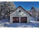 Detached two-car garage with snow covered roof surrounded by snowy trees at 2880 Lake Meadow Dr, Monument, CO 80132