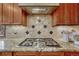 Kitchen cooktop set into granite counters with tiled backsplash at 2880 Lake Meadow Dr, Monument, CO 80132