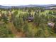 Scenic aerial view of the home with a large deck nestled in a lush, green landscape with mountain views at 29663 Paint Brush Dr, Evergreen, CO 80439