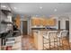 Bright kitchen with stainless steel appliances, wood floors, breakfast bar, open shelving and black countertops at 29663 Paint Brush Dr, Evergreen, CO 80439