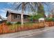 Traditional brick house with a picket fence, green lawn, mature trees, and a two-car garage with an extended driveway at 3150 S Pitkin St, Aurora, CO 80013